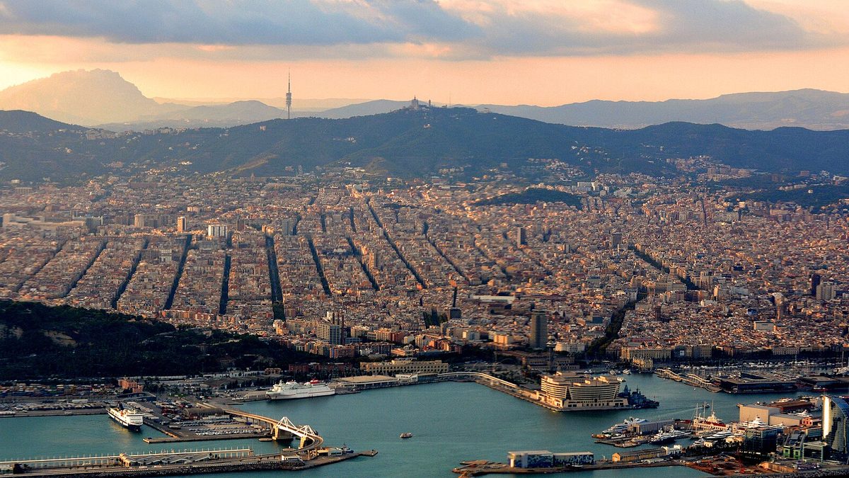 Evening light over Barcelona's city grid and port, with Montserrat on the horizon
