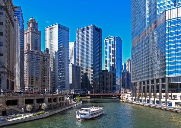 A tour boat on the Chicago River below downtown skyscrapers