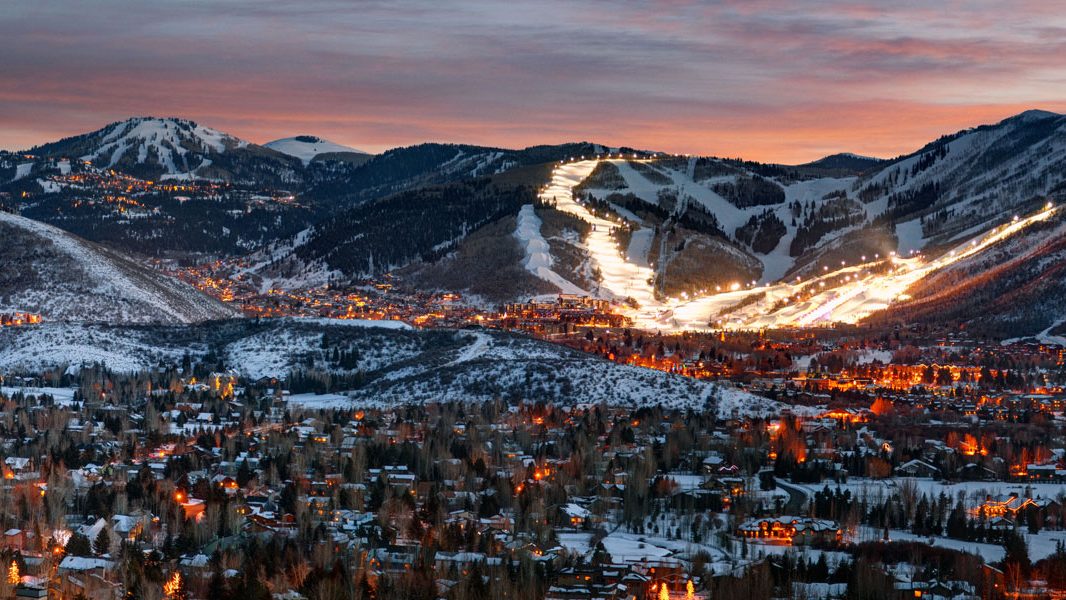 Park City at dusk in winter, with lit ski runs on the mountain above town